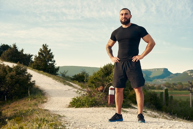 Foto uomo sportivo in piedi sulla collina in campagna