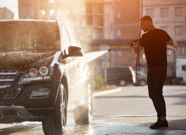 Sporty man washing his black car outdoors