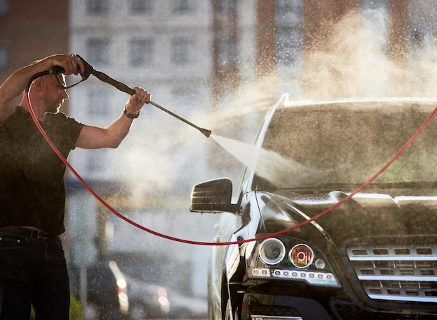 Sporty man washing his black car outdoors