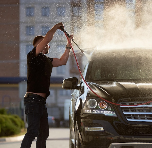 Sporty man washing his black car outdoors