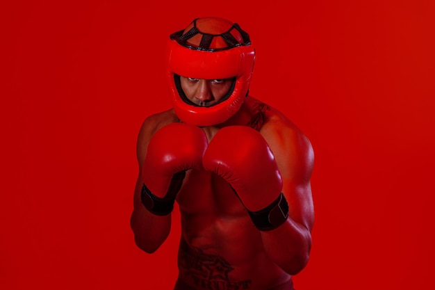 Фото Спортивный мужчина в защитном шлеме и боксерских перчатках тренируется перед боем в студии