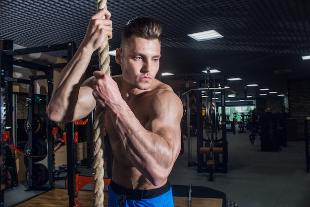 Sporty man with big muscles and a broad back trains in the gym, fitness and pumped-up abdominal press