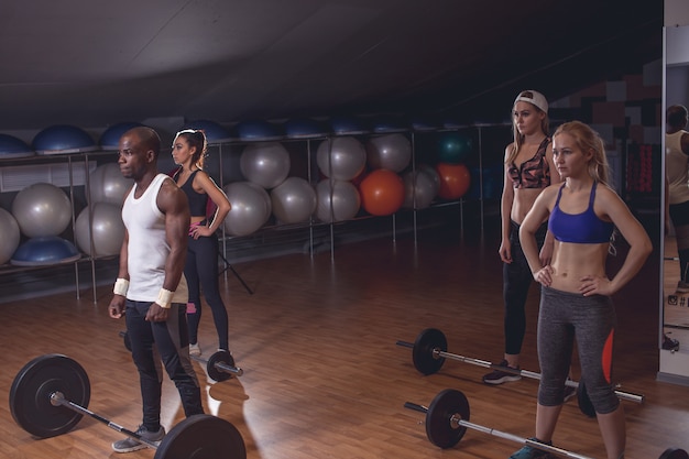 Sporty man and womans preparing to do exercise with barbells. Horizontal indoors shot