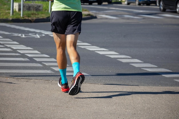 A sporty person runs down the street with blue socks and red boots on his feet