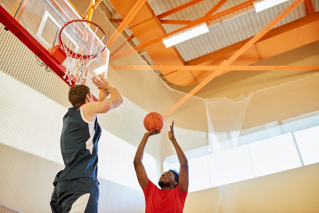 Sporty player throwing ball in basket