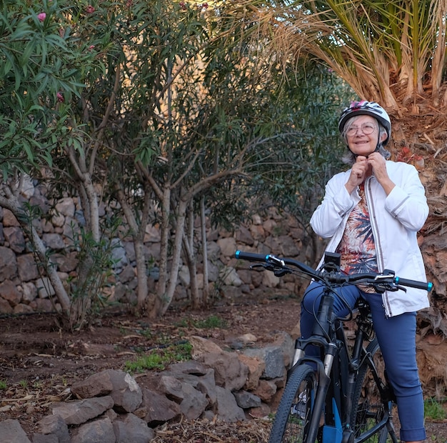 Sporty senior woman with helmet in outdoors activity with electric bicycle