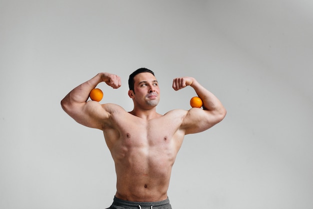 Sporty sexy guy posing on a white background with bright fruits. Diet. Healthy diet