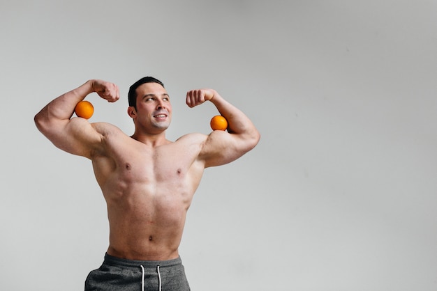 Sporty sexy guy posing on a white background with bright fruits. Diet. Healthy diet.