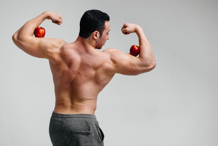Photo sporty sexy guy posing with bright fruits. diet. healthy diet