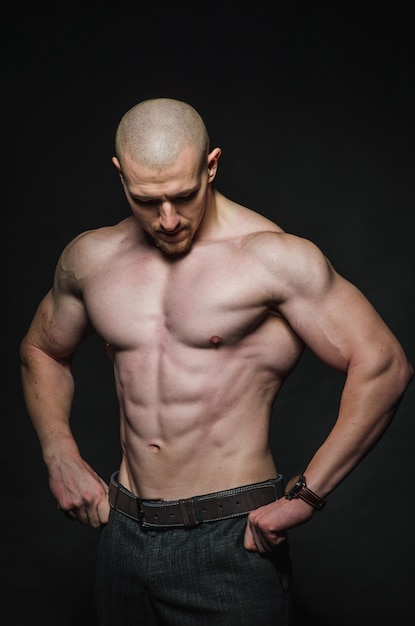 Sporty sexy man stands Topless on a dark background. Sports, beauty.