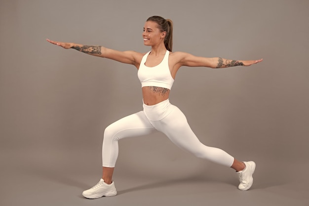 Sporty strong cheerful young woman posing on gray isolated background Caucasian female athlete muscular sportive woman Concept of youth healthy lifestyle