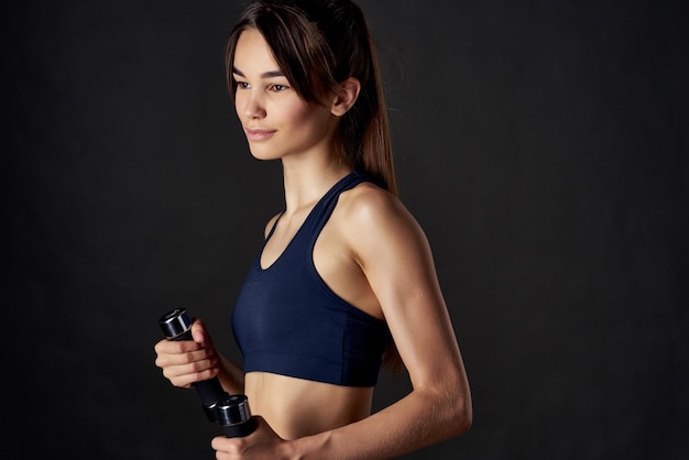 Sporty woman in black top with dumbbells in hands cropped view of workout exercise