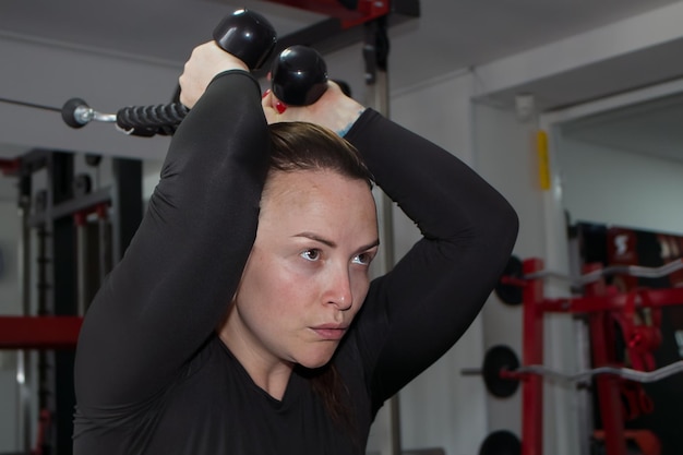 sporty woman doing back exercises with weight in a gym