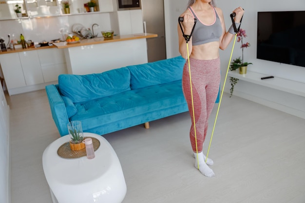 Sporty woman doing exercise with fitness rope at home