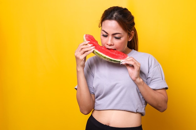 Sporty woman eating watermelon on a yellow background