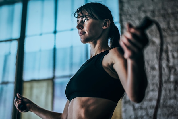 Donna sportiva che si esercita con la corda per saltare in palestra