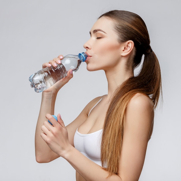Спортивная женщина на сером фоне питьевой воды