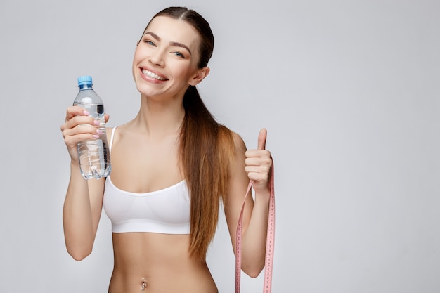 灰色の背景の飲料水の上のスポーティな女性