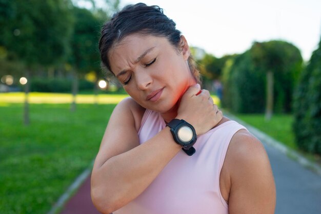 Foto donna sportiva che ha il dolore al collo all'aperto