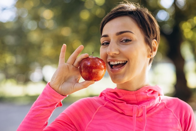 Photo sporty woman holding red apple in park