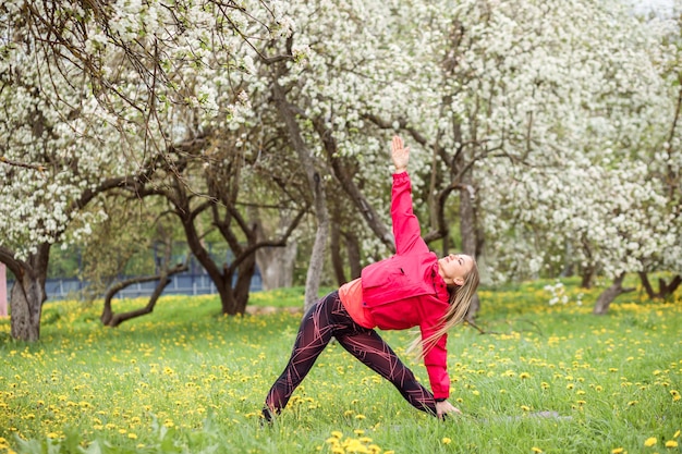 La donna sportiva sta esercitando, facendo esercizi di fitness all'aperto in primavera