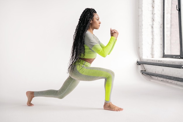 A sporty woman is a slim figure doing squat exercises in stylish modern fitness clothes