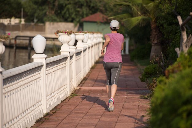 Photo sporty woman jogging on sidewalk at early morning