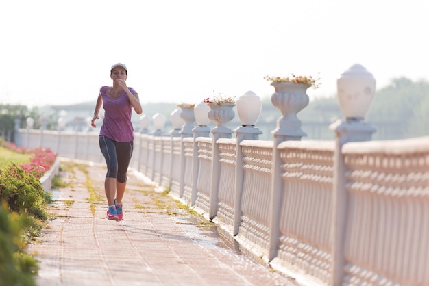 Sporty woman jogging on sidewalk at early morning