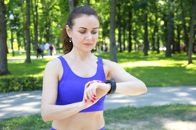 Sporty woman looks at the clock on his hand