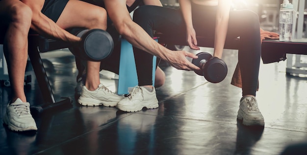 Sporty woman and man working out with trainer at fitness gym. Health and wellbeing lifestyle.