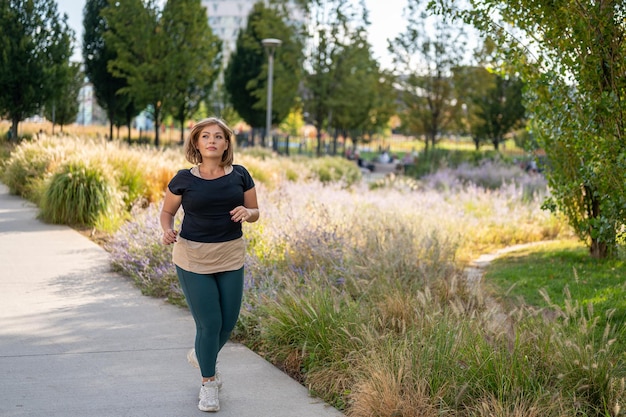 Photo sporty woman running outdoor body positive and healthy lifestyle concept curvy young girl jogging