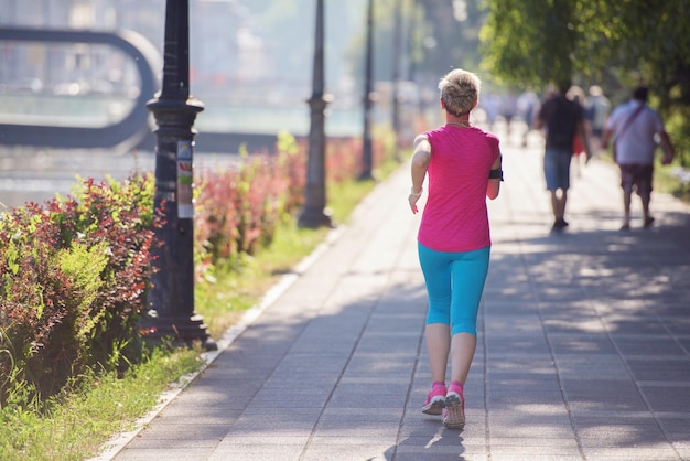 sporty woman running on sidewalk at early morning with city  sunrise scene in background