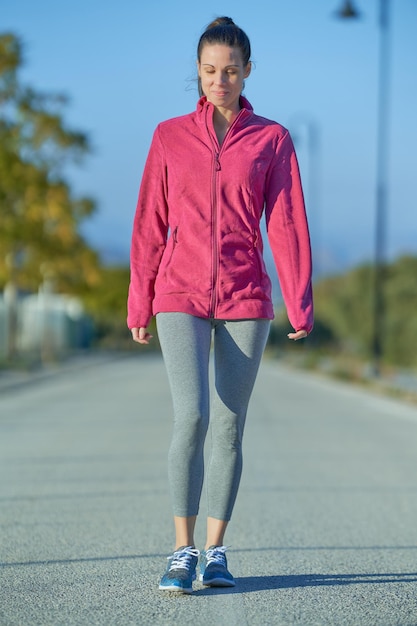 Sporty woman seen from the front walking down the street