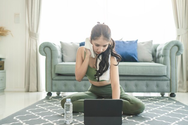 Una donna sportiva in abiti sportivi si esercita mentre guarda una sessione di esercizi online sul suo smartphone a casa