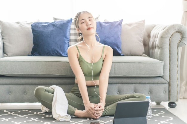 A sporty woman in sportswear exercises while watching online exercise session on her smart phone at home