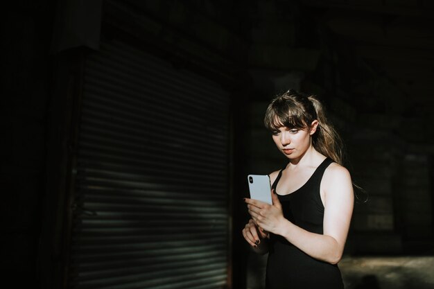 Donna sportiva che manda un sms in un vicolo scuro