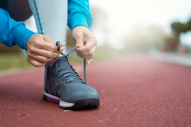 スポーティな女性はジョギングする前に彼女の靴を結ぶ