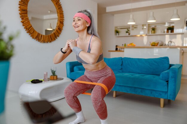 Photo sporty woman using resistance band during home workout