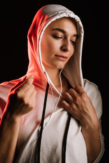 Sporty woman wearing hoodie ang earphones on black background