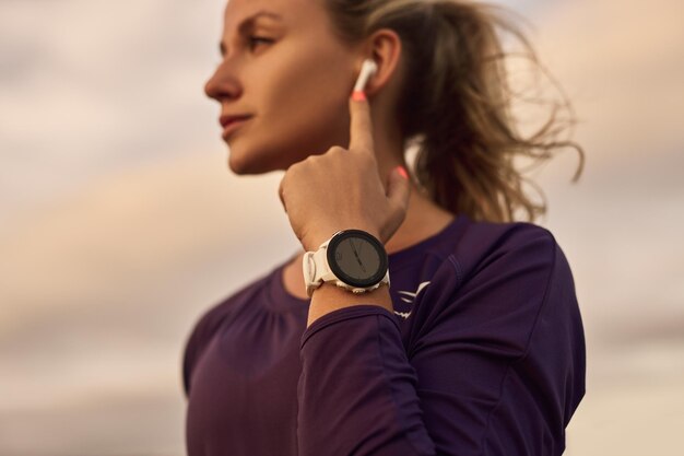 Foto donna sportiva con auricolari e smartwatch