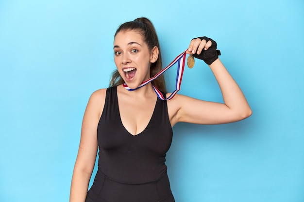 Photo sporty woman with a gold medal on a blue studio background