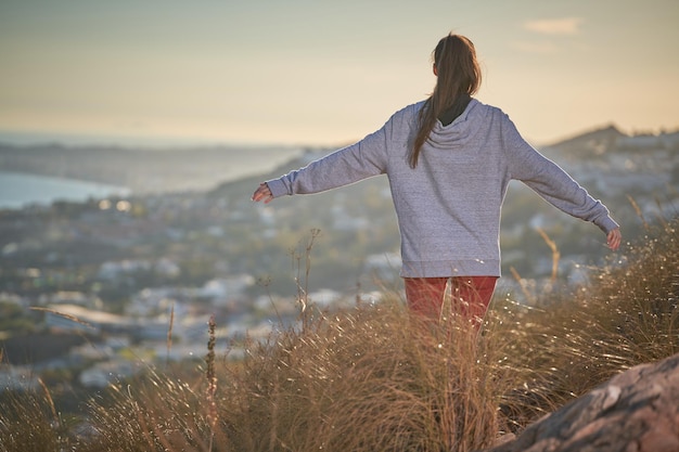 sporty woman with long hair and red leggings doing sport on mountain peak with valley hill view