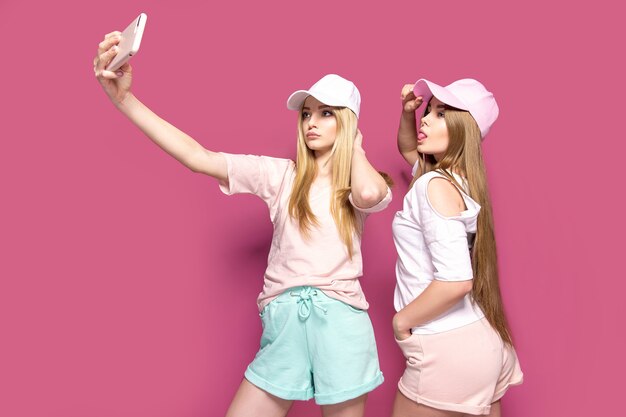 Sporty women taking selfie on pink wall