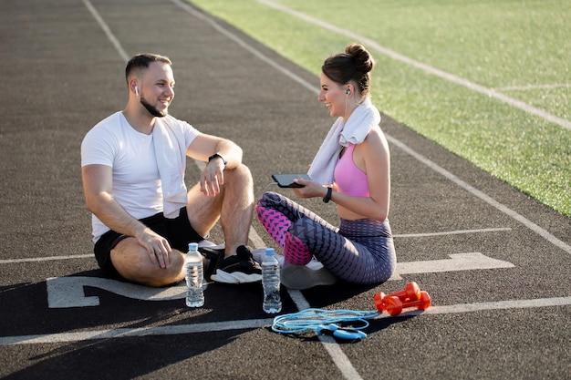 Photo sporty young boy and woman sit on the treadmill at the stadium in the summer