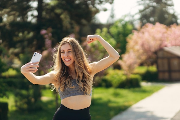 Sporty young girl with phone take selfie photo in the park