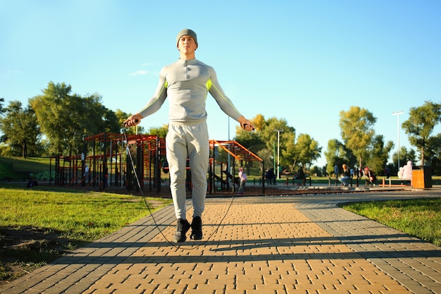 Sporty young man jumping rope in park