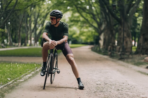 朝のサイクリングの後に公園で休んでいるスポーティな若い男