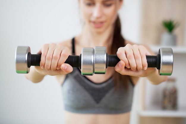 Sporty young woman doing exercising with dumbbells.