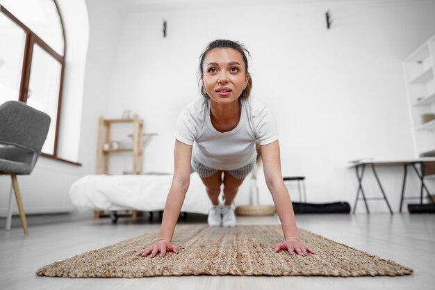 Sporty young woman doing plank exercise indoors at home