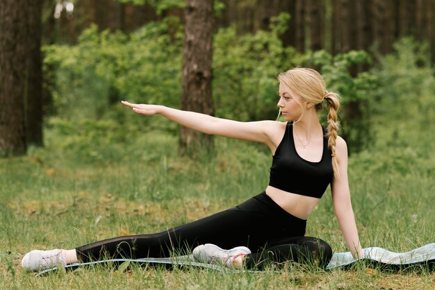 Sporty young woman doing yoga in the forest